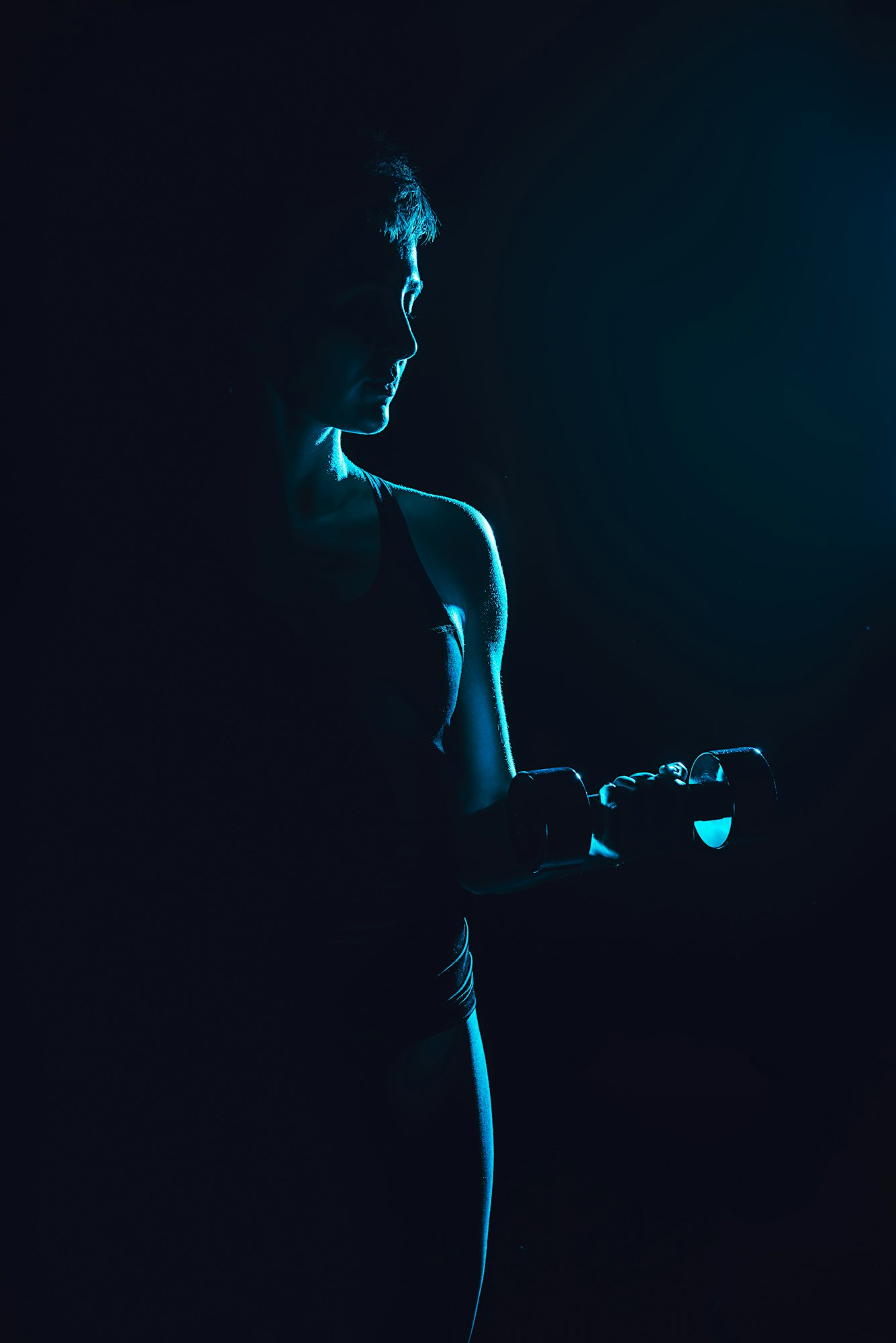 imagine tonifiată a unei atlete care se antrenează cu gantere, fundal negru