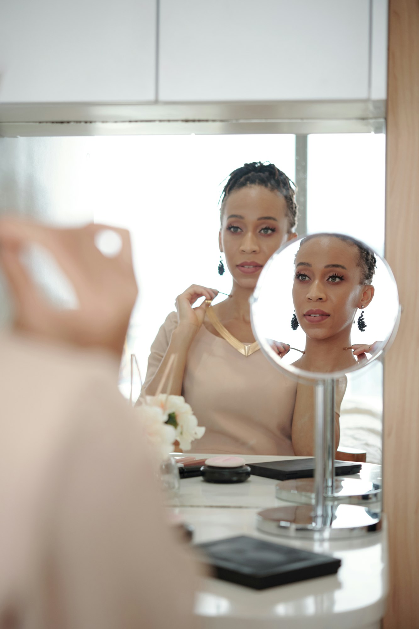 Femeie frumoasă care se uită în oglindă atunci când alege bijuterii pentru ținuta ei