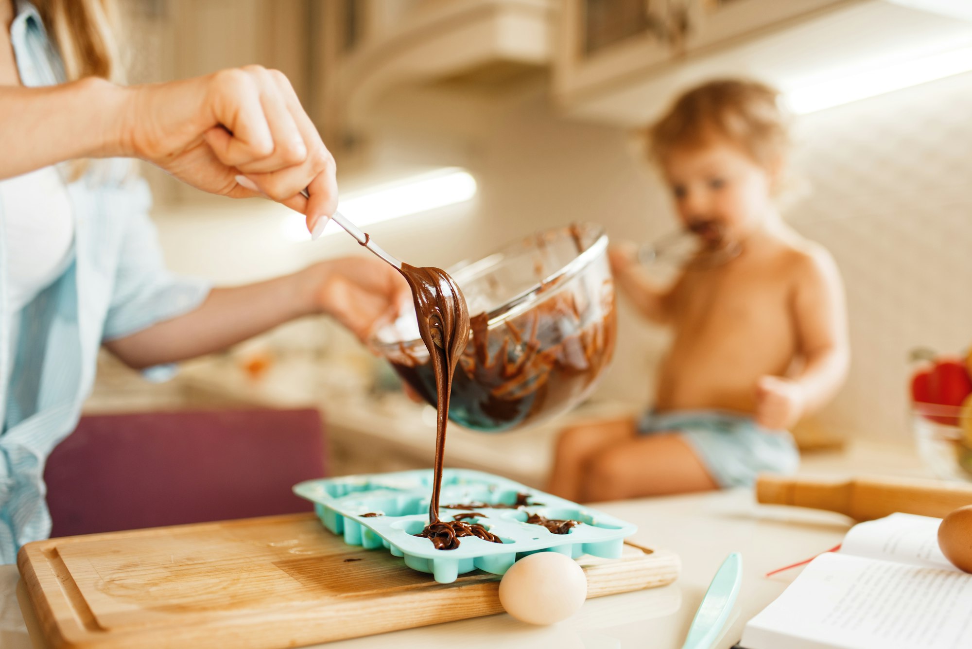 Tânăra mamă și copilul pregătesc produse de patiserie și gustă ciocolată topită.