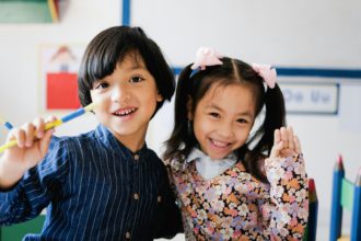 Copii asiatici fericiți care se distrează în sala de grădiniță.