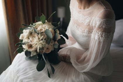 O mireasă în mână cu un buchet de flori albe.