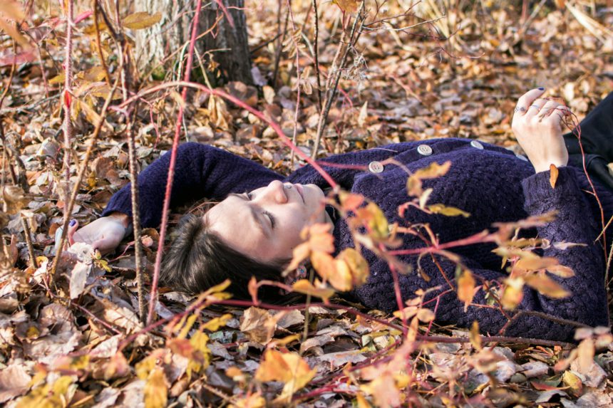 O femeie care se conectează pașnic cu natura într-o pădure senină de toamnă.