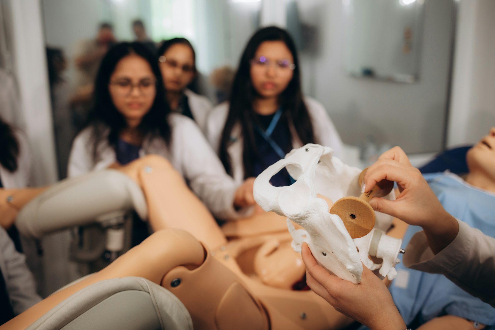Un grup de studenți la ginecologie efectuează exerciții practice de reproducere a proceselor de naștere pe un manechin.