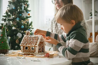 Copil cu mama decorând împreună casa de turtă dulce de Crăciun, activități de familie și tradiții de Crăciun și Revelion