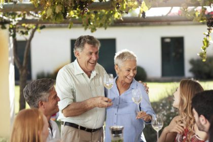 Cuplu de seniori fericit cu familia luând prânzul împreună afară