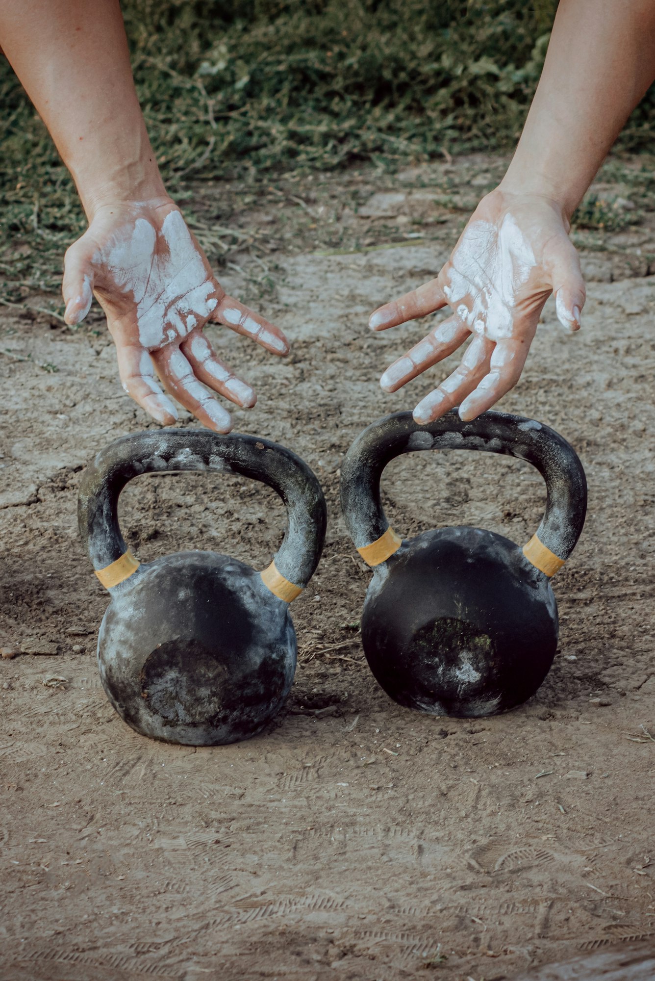 Mâini în pulbere de magnezie și kettlebell pentru antrenament funcțional.