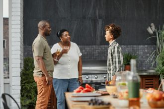 Portret de familie afro-americană modernă cu fiul adolescent care se bucură de cina la terasa în aer liber, spațiu de copiere