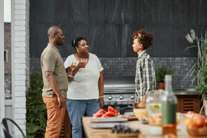 Portret de familie afro-americană modernă cu fiul adolescent care se bucură de cina la terasa în aer liber, spațiu de copiere