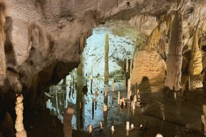 Lacul interior din peștera carstică cu stalactite și stalagmite.