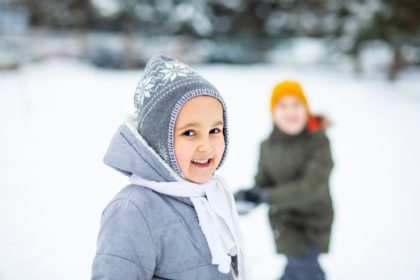 Băiat și fată adolescent fericiți care se joacă cu bulgăre de zăpadă în aer liber în natură.