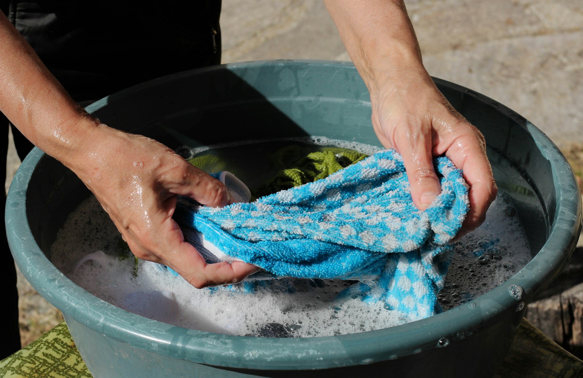 Femeie care spală haine în plămâni în aer liber, aproape, zi de spălătorie, teme, treburi casnice, muncă, rural, stil de viață, bule de săpun, spumă, curățare, igienă