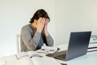 Tânăr student folosind laptop care lucrează de acasă pe internet.