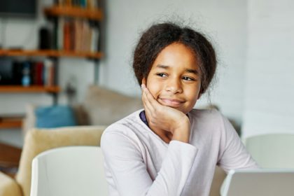 Portretul unei adolescente distrându-se folosind laptopul sau făcând temele cu laptopul acasă