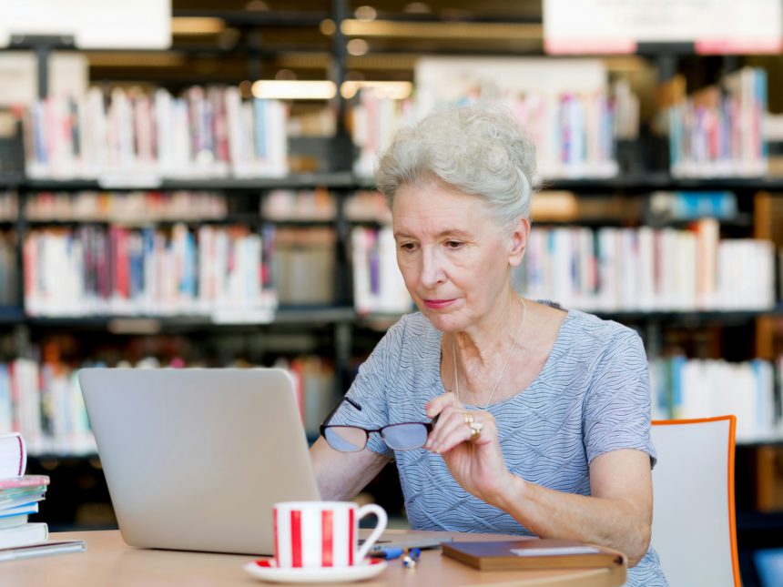 Doamnă în vârstă care lucrează cu laptop